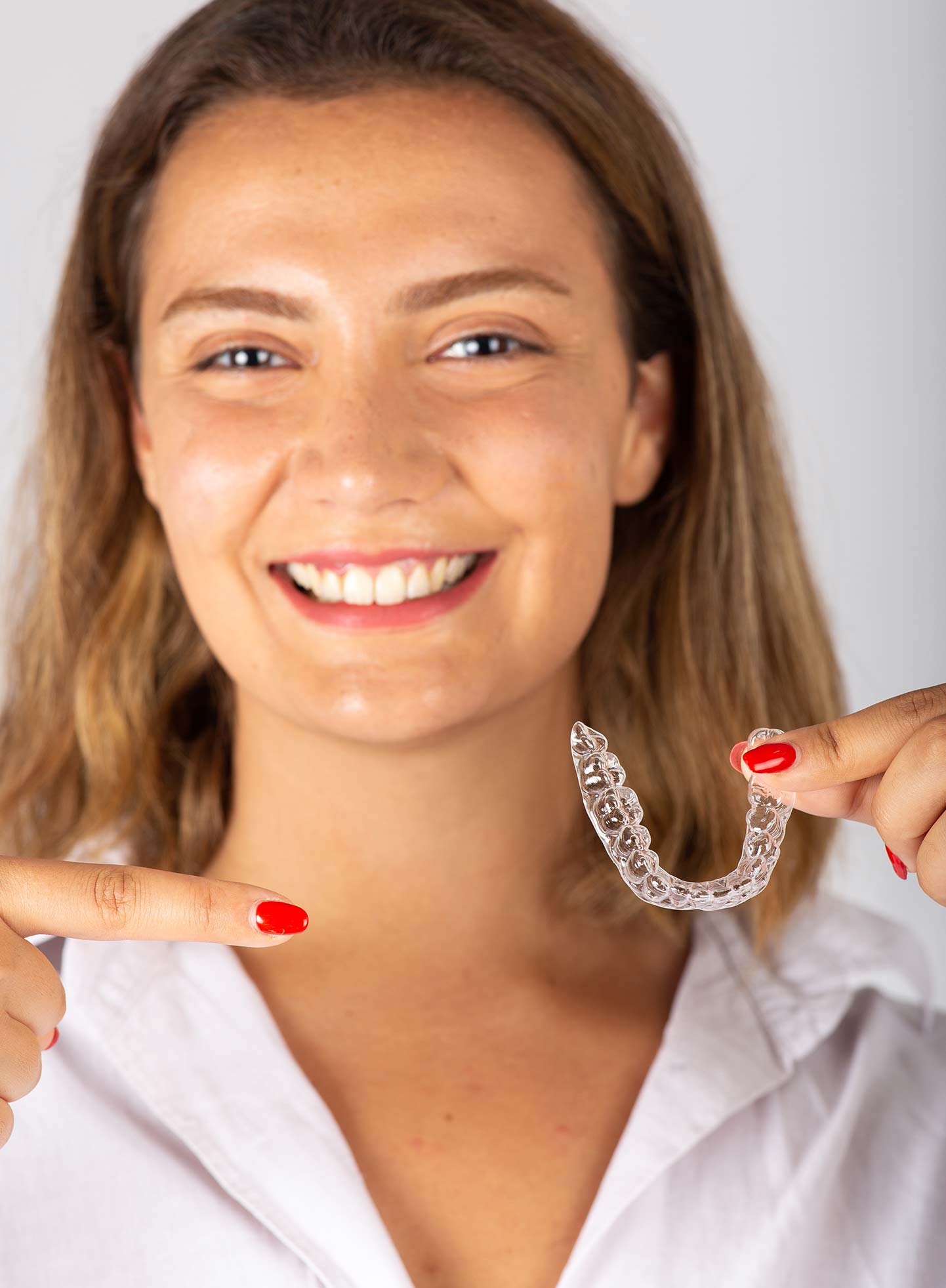 A young girl holding her dental aligner