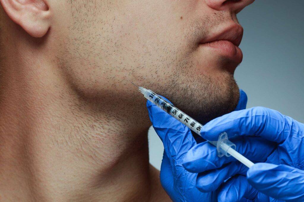 a young man injecting botox into jawline