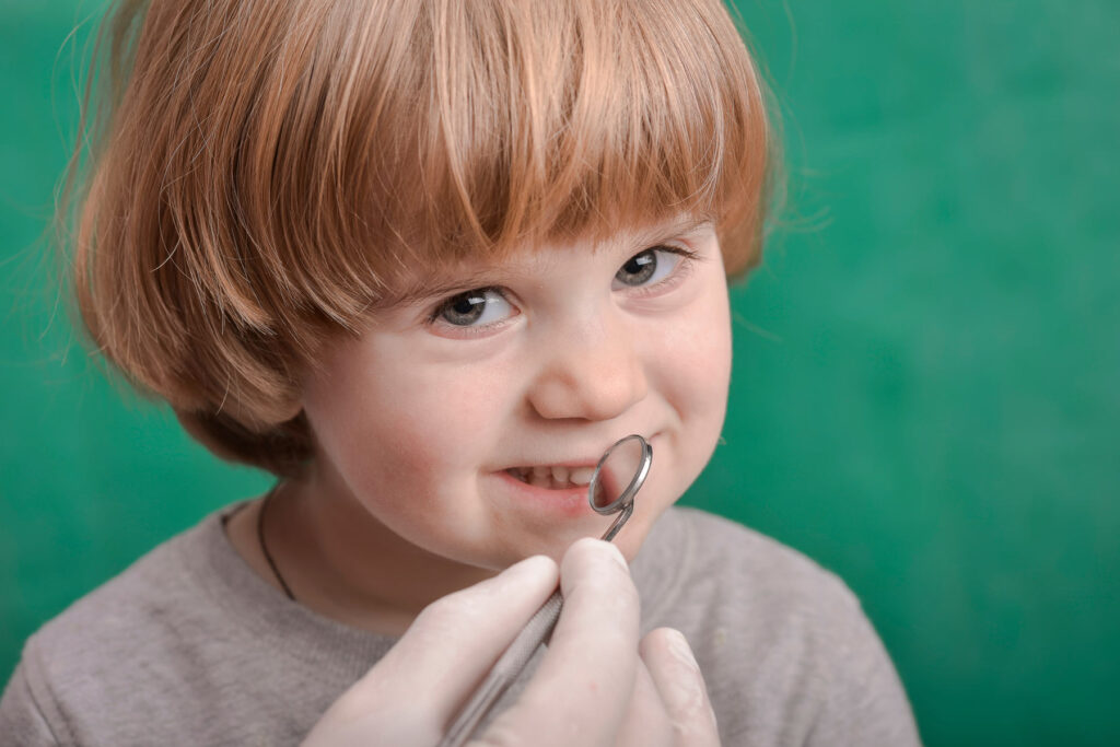 dentist examining a child teeth while he is smiling